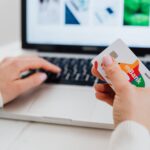 close up shot of a person using a laptop while holding a credit card