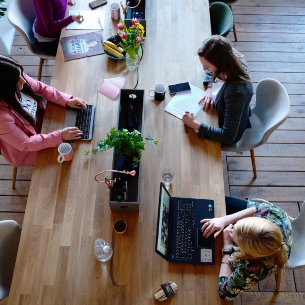 three woman sitting on white chair in front of table