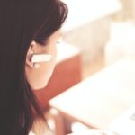 woman wearing earpiece using white laptop computer