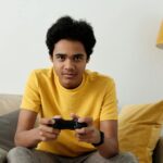man in yellow crew neck t shirt sitting on bed