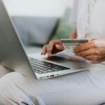 person using a macbook and holding a credit card