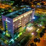 hospital beside vehicle park and road at night