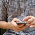 man in plaid shirt using smartphone