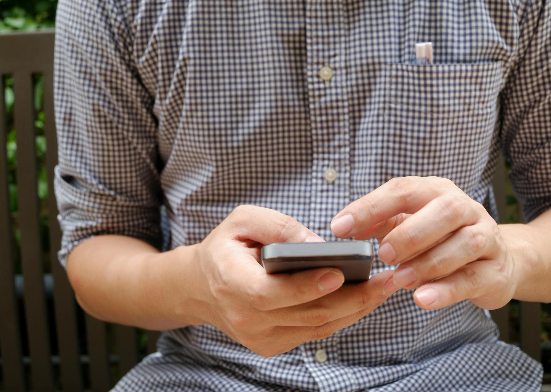 man in plaid shirt using smartphone
