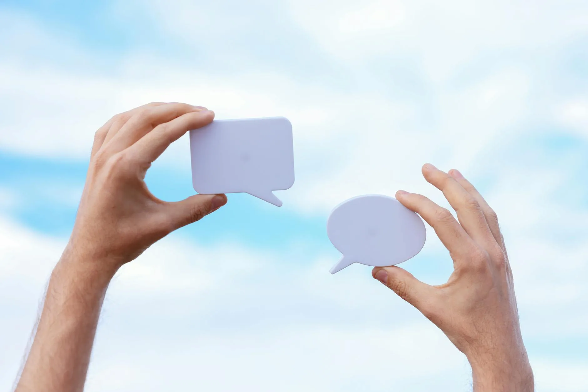 close up of man holding paper cutouts in the shape of conversational clouds