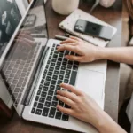 crop female freelancer using laptop at table at home