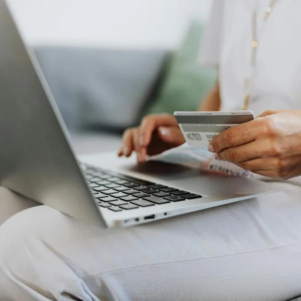 person using a macbook and holding a credit card