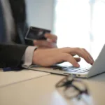 person in black suit typing on a computer